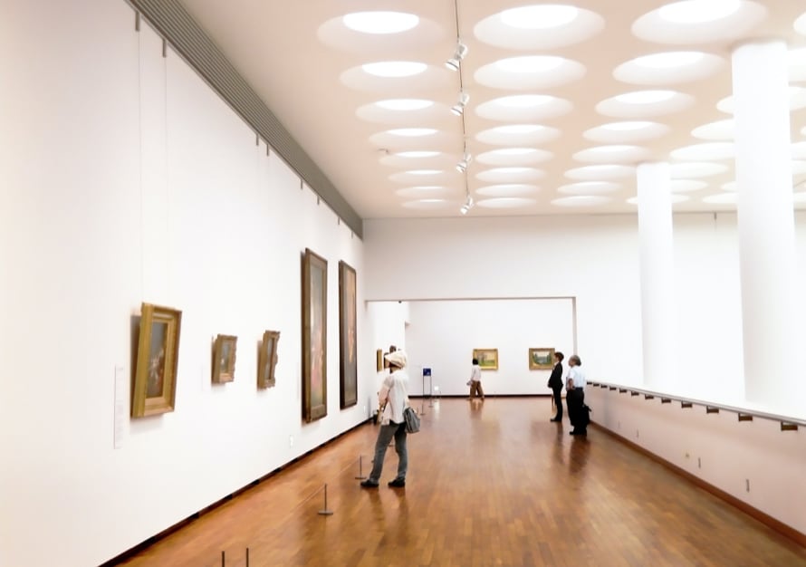 Hall of museum, where several people are standing and looking at pictures