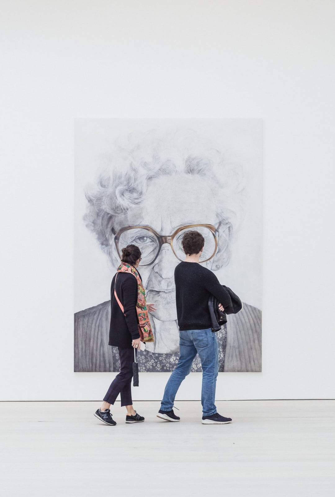 Man and woman standing and looking at picture of old woman