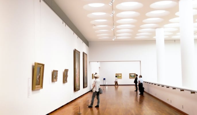 Hall of museum, where several people are standing and looking at pictures