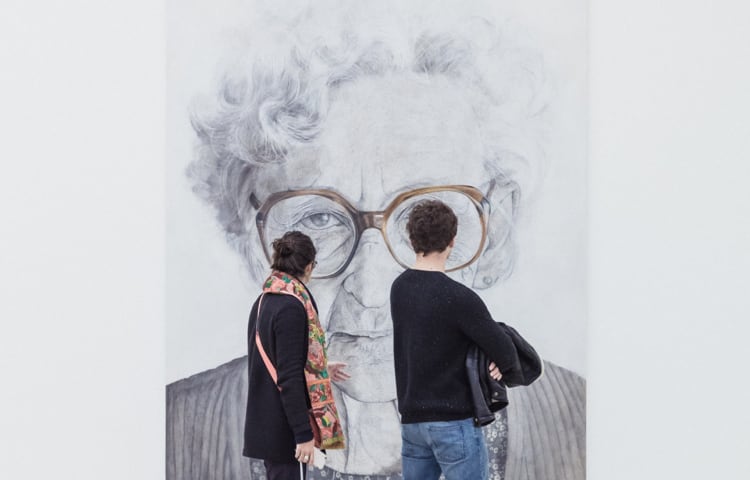 Man and woman standing and looking at picture of old woman
