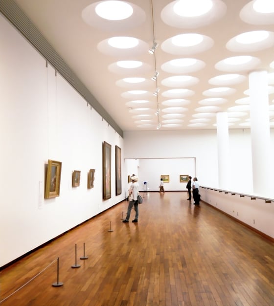Hall of museum, where several people are standing and looking at pictures