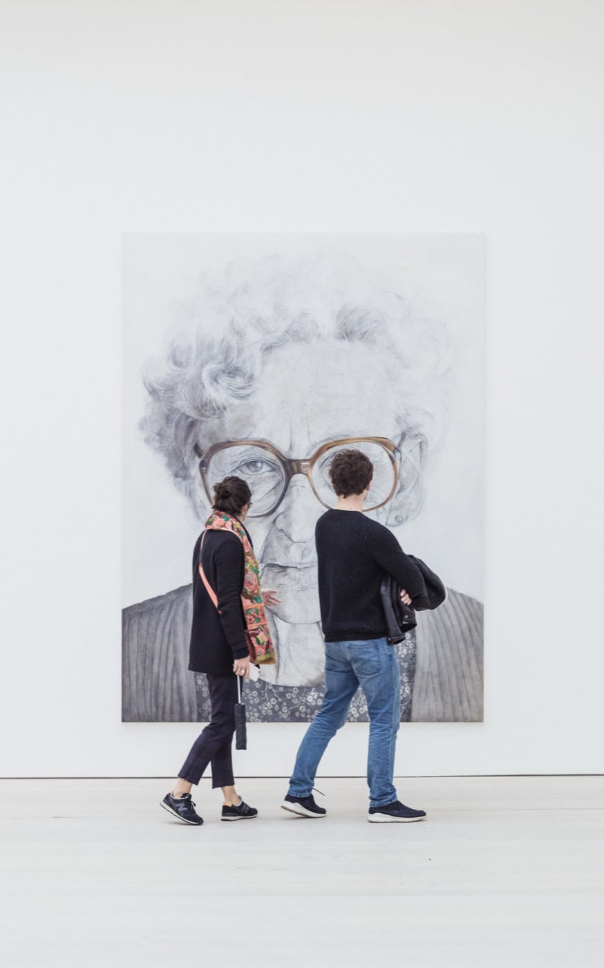 Man and woman standing and looking at picture of old woman